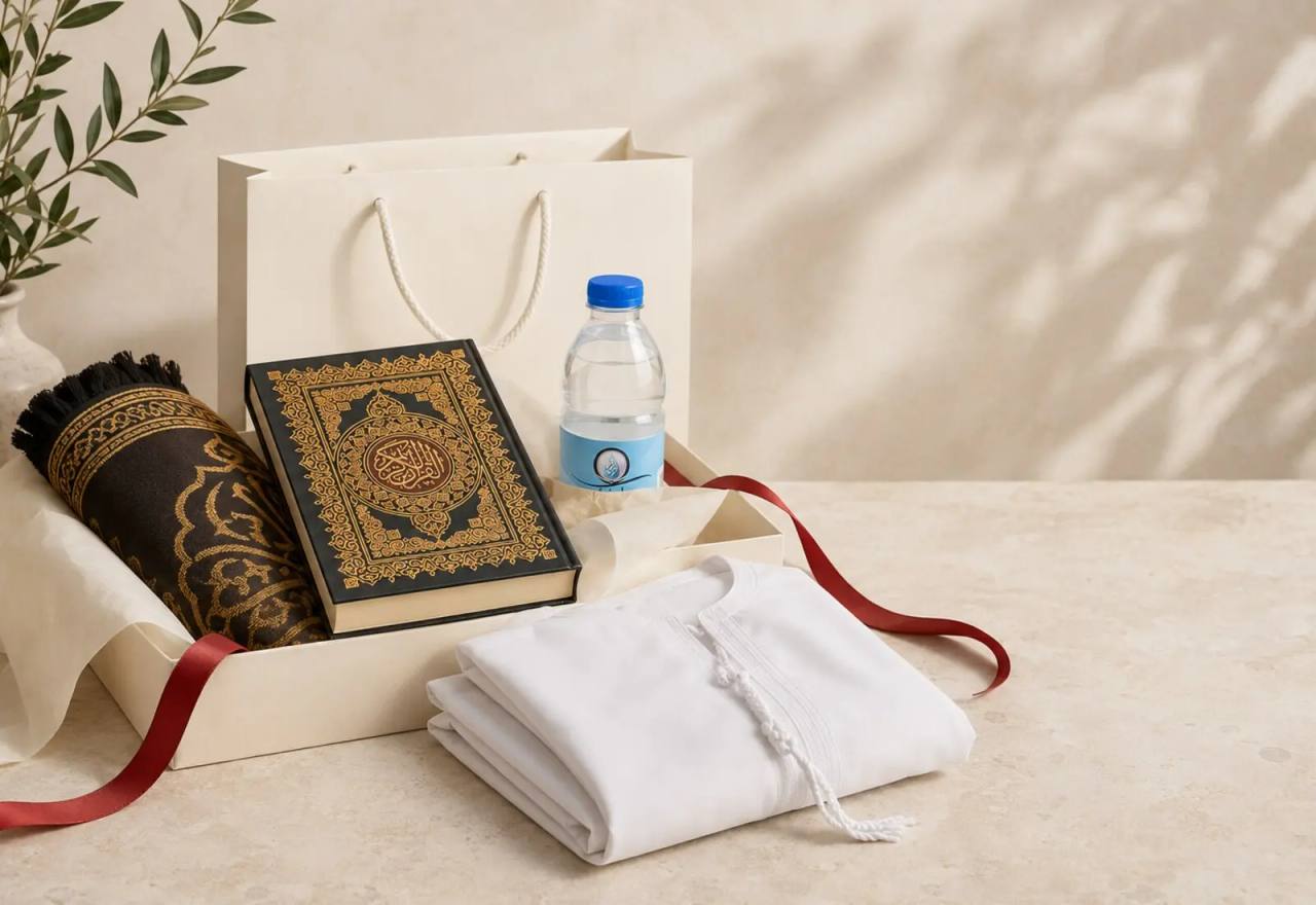 A calm welcome arrangement with a prayer mat, Quran, gift bag, bottled water and folded white garment