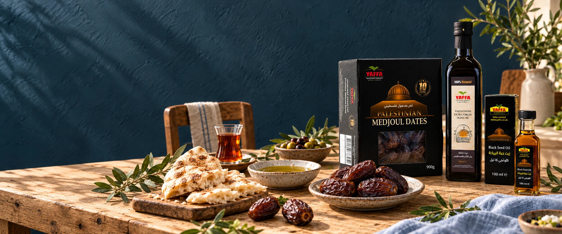 Yaffa Medjoul dates, olive oil and black seed oil on a table with bread, dates and tea.